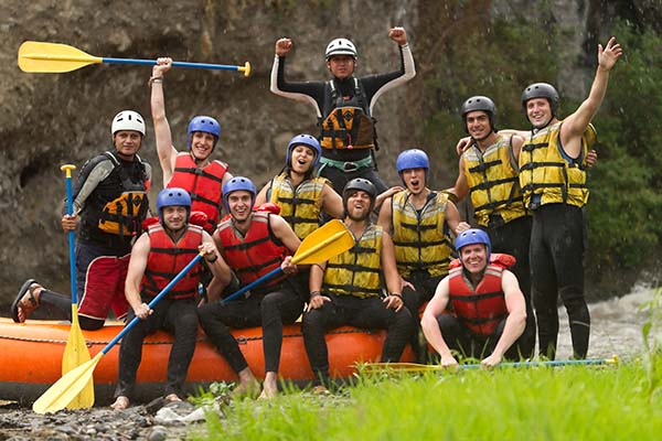 Group of people in rafting gear excited after thrilling experience